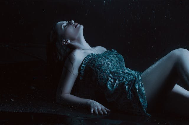 Femme assise sous la pluie, &eacute;clairage dramatique