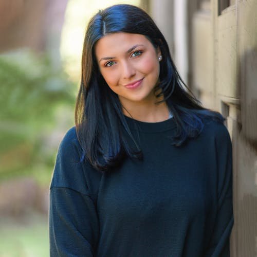 Femme souriante aux cheveux noirs, en ext&eacute;rieur